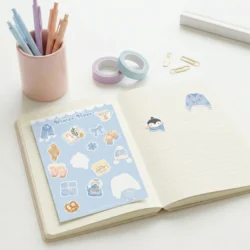 Planche de stickers Winter Vibes et ses motifs déjà collés sur un carnet ouvert by La Crafty House