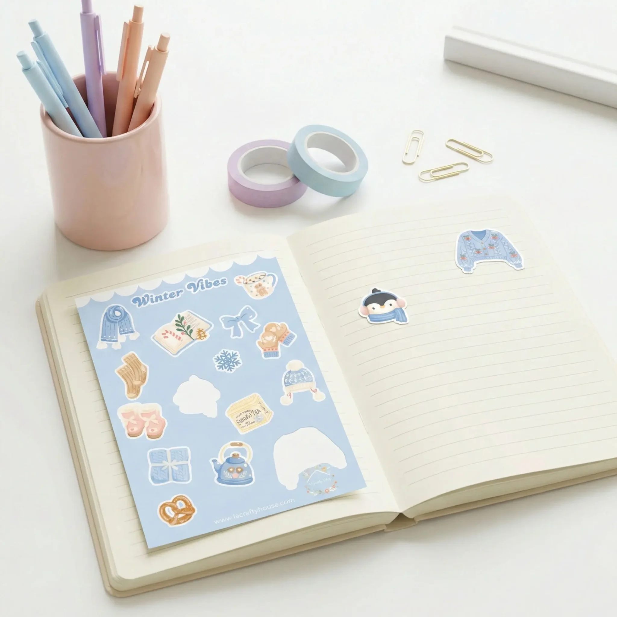 Planche de stickers Winter Vibes et ses motifs déjà collés sur un carnet ouvert by La Crafty House