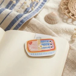 Marque-page magnétique Brise Salée en boîte de sardines, plié sur la page d'un carnet ouvert by La Crafty House